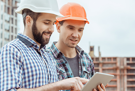 2 Deux hommes sur un chantier échangent au sujet de la dématérialisation des marchés publics depuis une tablette