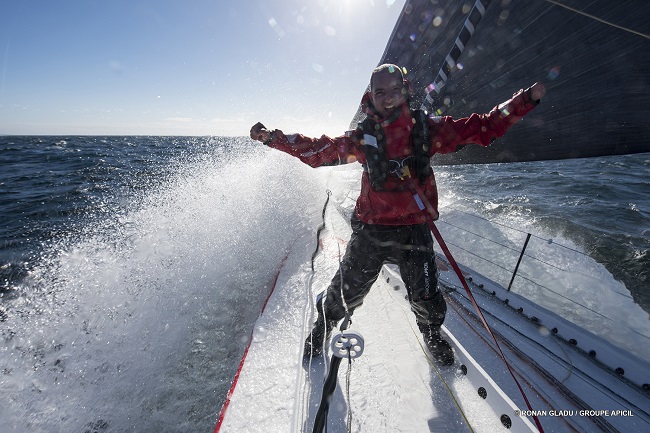 Damien Seguin sur son bateau durant le Vendée Globe les bras levés en l'air sur la poupe de son bateau en pleine vague qui déferle