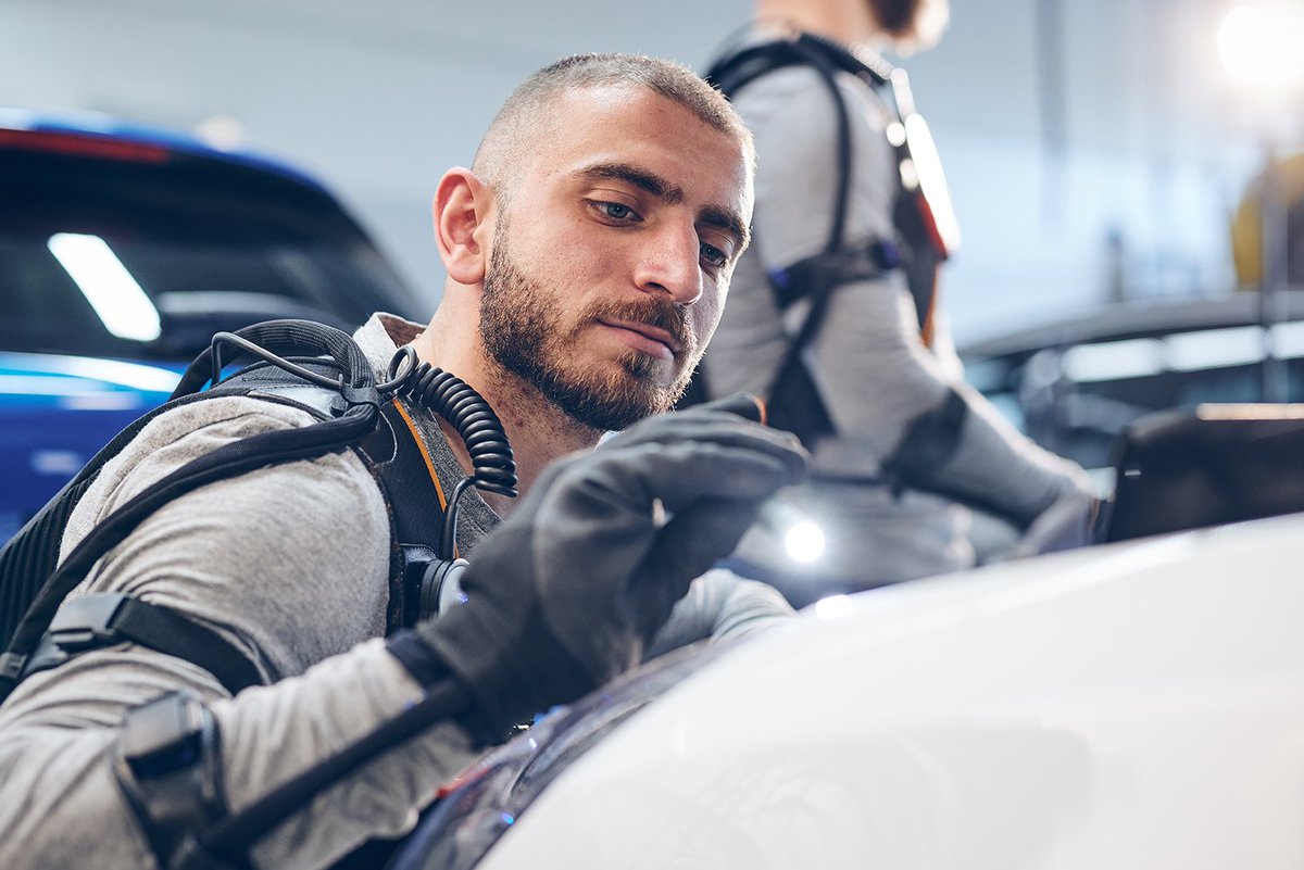 Un homme travaille sur une voiture avec le gant bionique d'Eiffage présenté à Fimbacte 2019