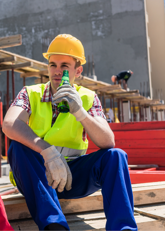 Un ouvrier sur un chantier avec une bière à la main alors qu'il est sur son lien de travail dans le cadre de la prévention de la consommation d'alcool sur les chantiers par Janvier sobre