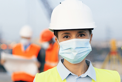 2 Une femme du BTP en premier plan avec son masque chirurgical pour se protéger contre le coronavirus sur les chantiers