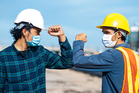 2 Deux ouvrier ses disent bonjours avec le coude et masqués sur un chantier pour évoquer les informations relatives au déconfinement et à la reprise d'activité des entreprises du BTP