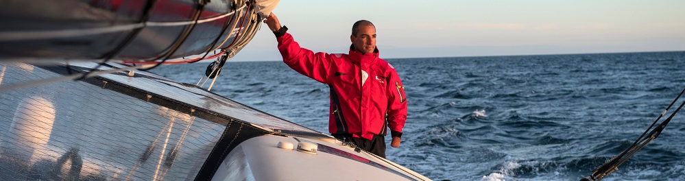 Photographie de damien seguin sur son bateau regardant à l'horizon en haute mer