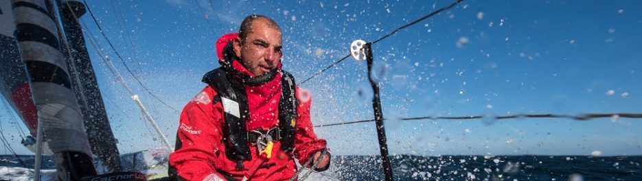 Photographie de damien seguin en pleine houle en haute mer et en train de réaliser des actions de sécurité sur son bateau