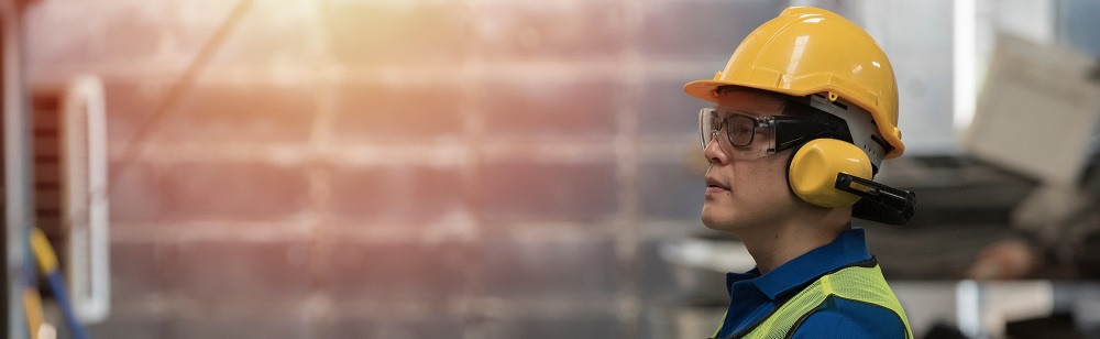 Un ouvrier sur un chantier porte son casque, ses lunettes et son casque anti-bruit pour éviter les séquelles liés à des bruits trop intenses