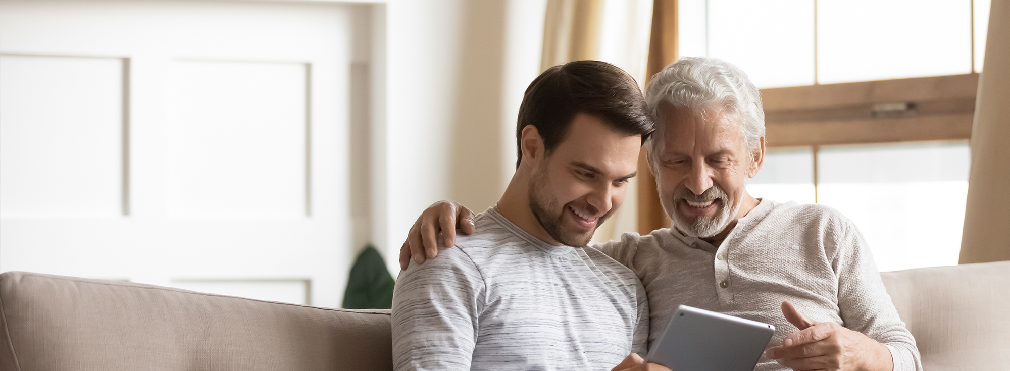 3 Un jeune homme parle de la téléassistance avec son grand père assis dans une canapé