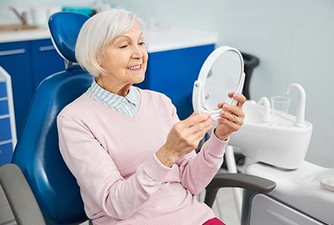 1 Femme âgée chez le dentiste qui regarde ses dents dans le cadre des soins pour les plus de 60 ans1